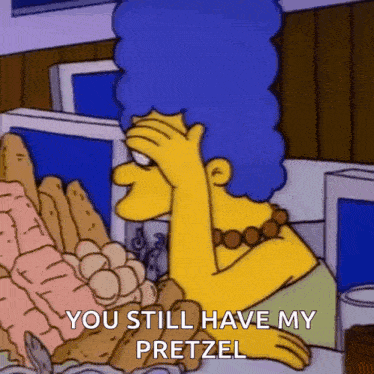 marge simpson from the simpsons is sitting at a table with pretzels and holding her hand to her forehead .