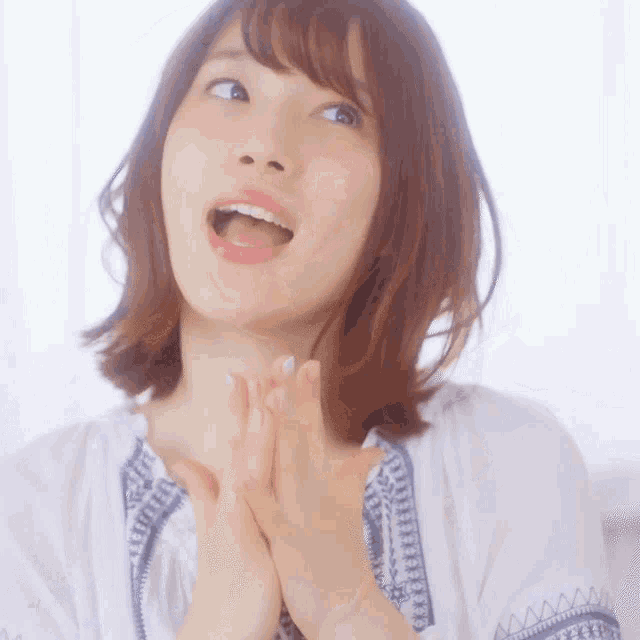 a woman with her mouth open is wearing a white and blue shirt