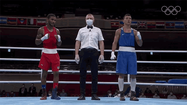 a referee wearing a mask stands between two boxers