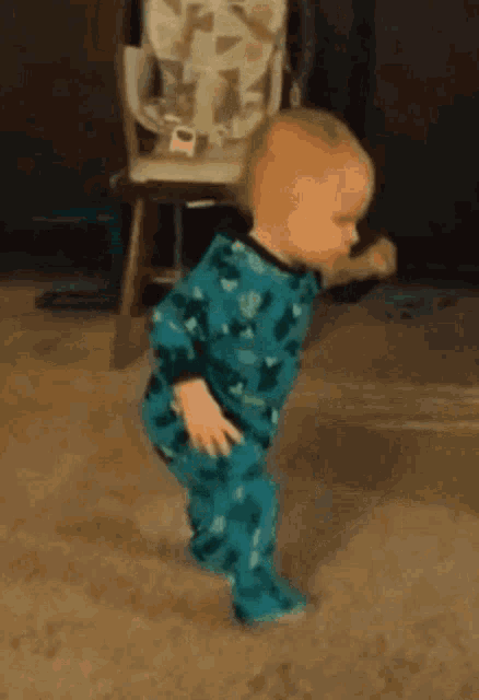 a baby in a blue pajama set is walking on the floor