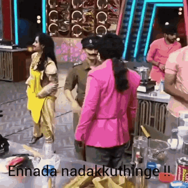 a woman in a pink jacket is standing next to a man in a yellow apron .