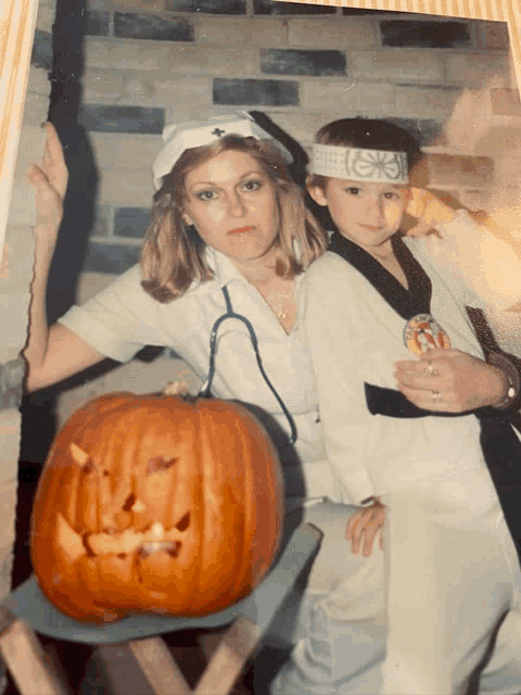 a woman in a nurse costume is holding a child in a karate outfit