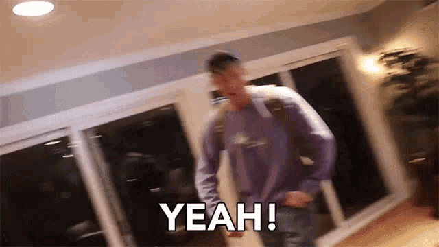a man in a purple shirt is dancing in a room with the words yeah written on the bottom