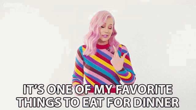 a woman with pink hair is wearing a colorful striped sweater and says it 's one of my favorite things to eat for dinner