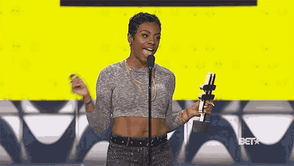 a woman in a crop top is holding a trophy and speaking into a microphone at a bet event