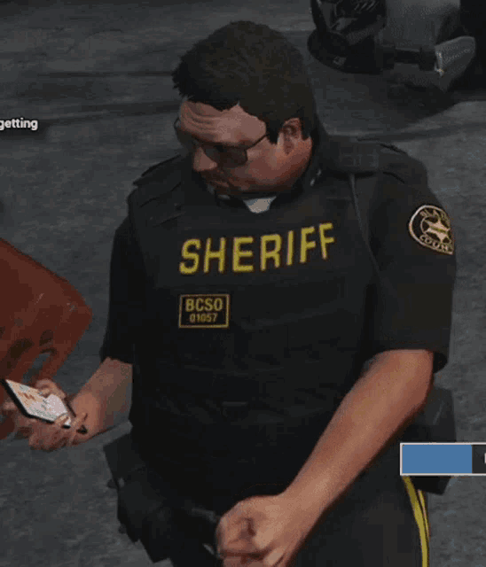 a man in a sheriff uniform is looking at a cell phone
