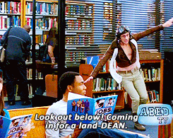 a man sitting in a library with a sign that says ' look out below coming in for a land - dean '