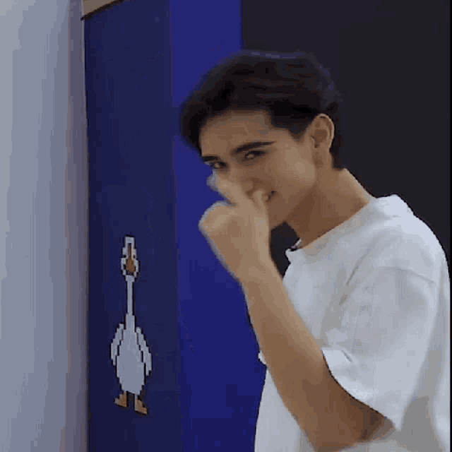 a man in a white shirt is making a funny face in front of a picture of a goose .