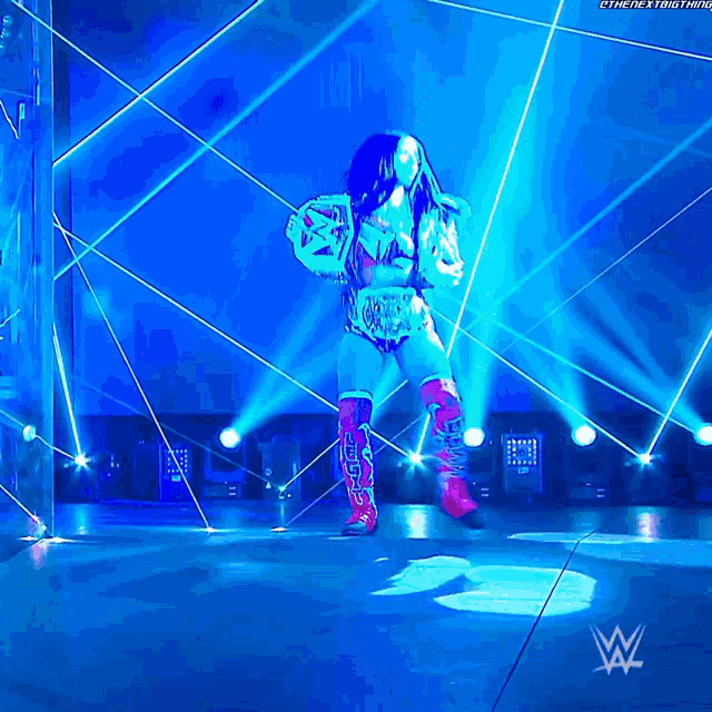 a woman in a wrestling outfit is on a stage with the letters w on the bottom