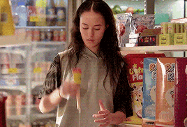 a woman is standing in front of a shelf with a bag of rice krispies