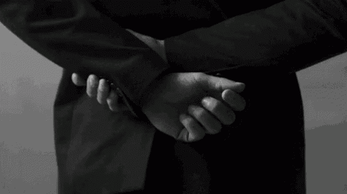 a black and white photo of a man with his hands behind his back