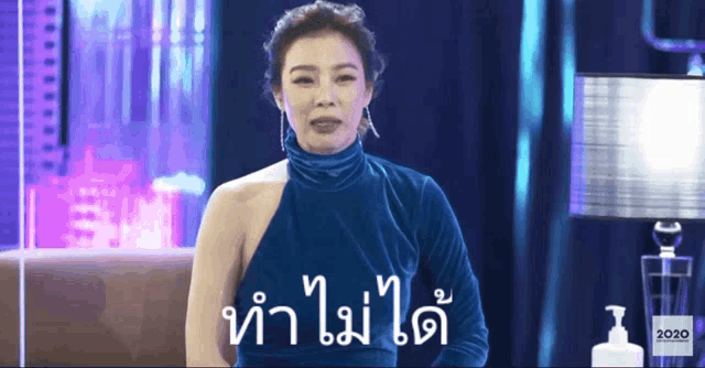 a woman in a blue dress stands in front of a sign that says ' 2020 '