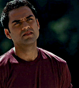 a man wearing a maroon shirt is making a face