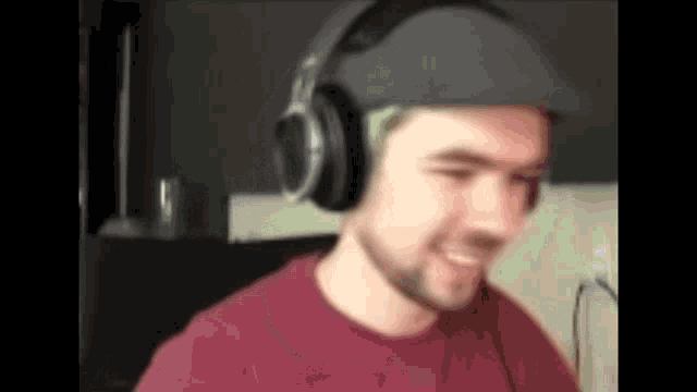 a man wearing headphones and a hat is smiling and looking at the camera .