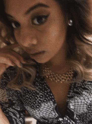 a woman wearing a necklace and earrings is looking at the camera