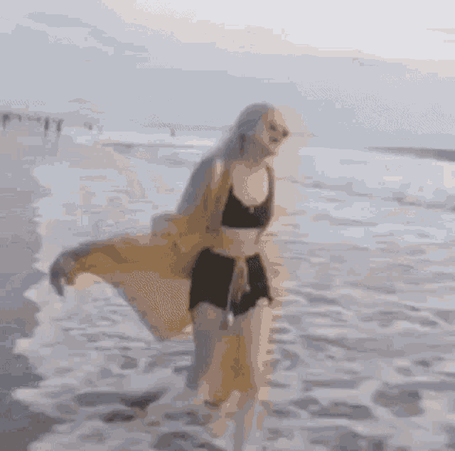 a woman in a bikini is walking on the beach in the water .