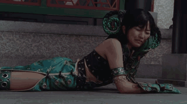 a woman in a green dress is laying on the ground