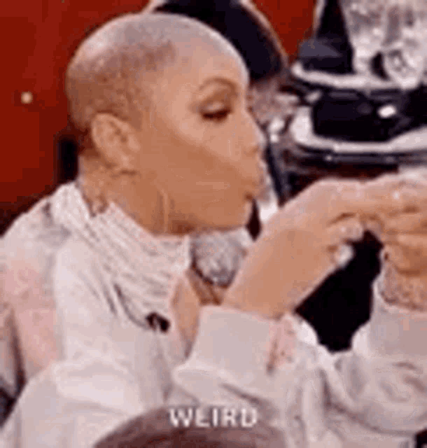 a woman with a shaved head is sitting at a table with a microphone .