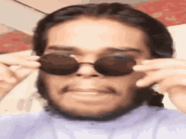 a close up of a man wearing sunglasses and making a face .