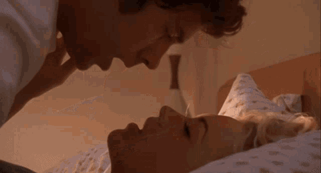 a man and woman are kissing in bed with a floral blanket