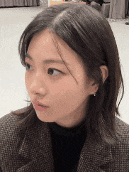 a close up of a woman 's face wearing a plaid jacket and black turtleneck .
