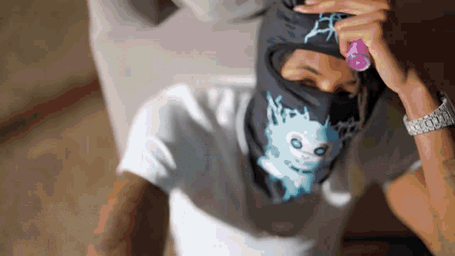 a man wearing a ski mask holds a purple object in his hand