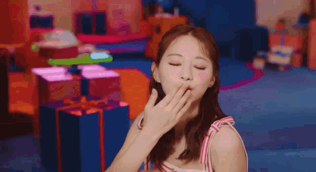 a woman is covering her mouth with her hand in a room with gifts .