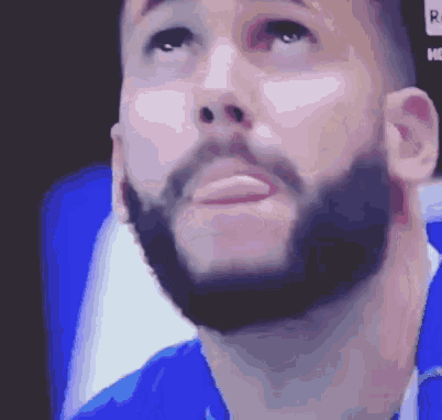 a man with a beard wearing a blue shirt is looking up