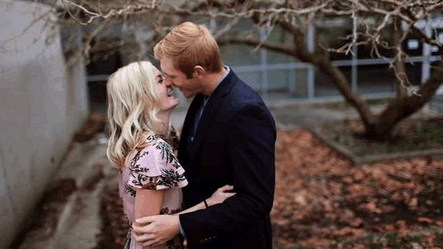 a man and woman are kissing under a tree