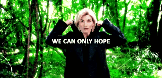 a woman in a black jacket is standing in a forest with the words `` we can only hope '' written on the screen .