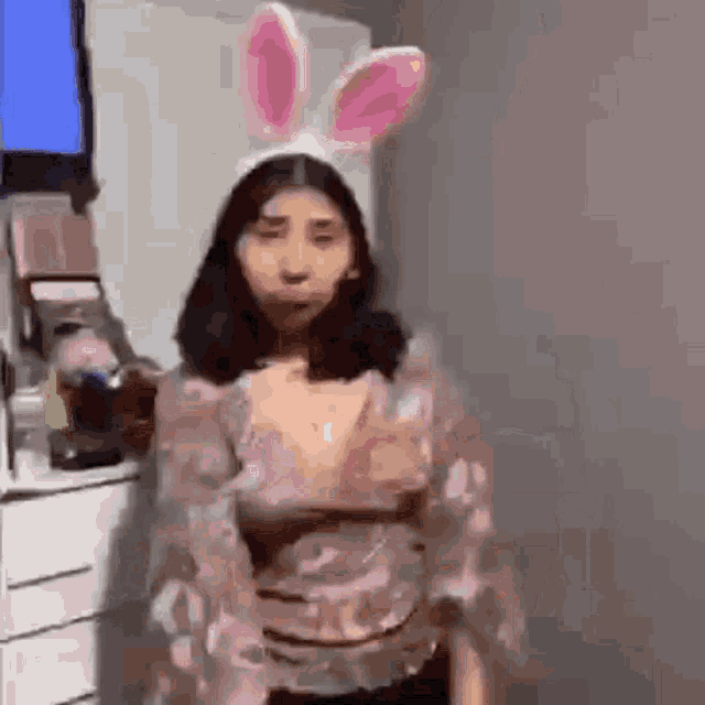 a woman wearing bunny ears is standing in front of a television in a room .