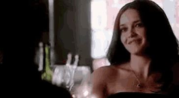 a woman in a strapless dress is smiling while sitting at a bar .