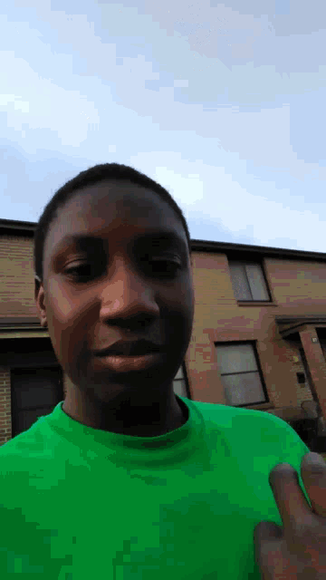 a young man in a green shirt is giving a peace sign