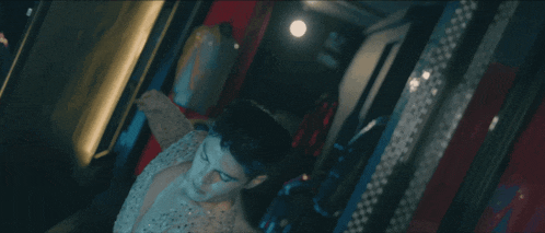 a man in a sequined shirt is sitting in a room