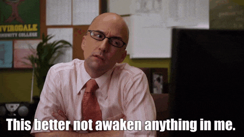 a bald man with glasses and a tie is sitting in front of a computer and says this better not awaken anything in me