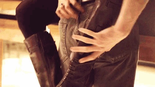 a close up of a person 's hands holding a pair of brown boots