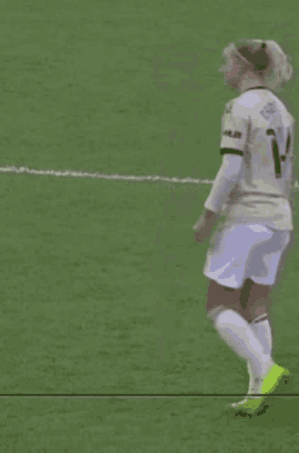 a soccer player wearing white shorts and yellow socks is running on the field .