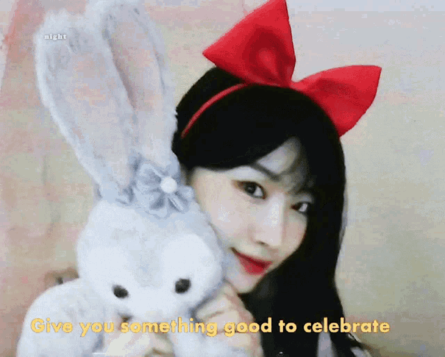 a girl with a red bow on her head is holding a stuffed bunny