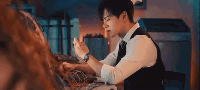 a man in a suit and tie is sitting at a desk looking at a computer screen .