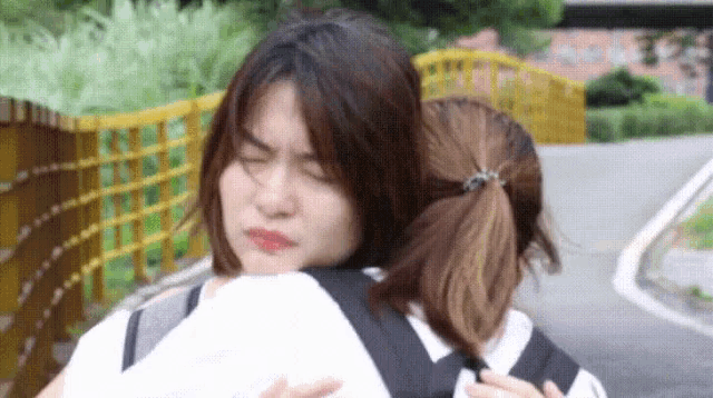 a woman is hugging another woman while making a face .