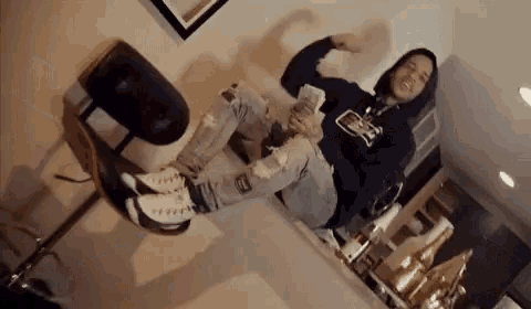 a man in a hoodie is sitting on a chair holding a bunch of money .