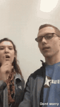 a man and a woman are standing next to each other and the man is wearing a blue shirt with a star on it