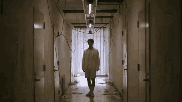 a man in a white lab coat stands in a hallway