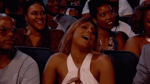 a woman is laughing while sitting in a crowd of people