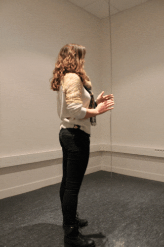 a woman standing in front of a mirror with her hands folded