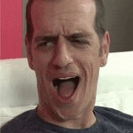a man is sitting on a bed with his mouth open and his tongue sticking out .