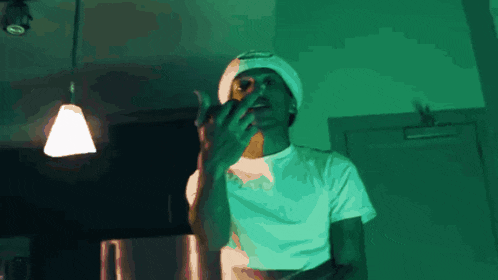 a man wearing a white hat and a white t-shirt is giving a middle finger