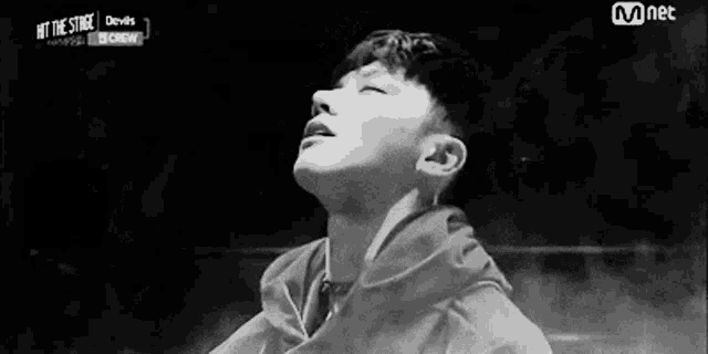 a black and white photo of a young man with his eyes closed and a hoodie on .