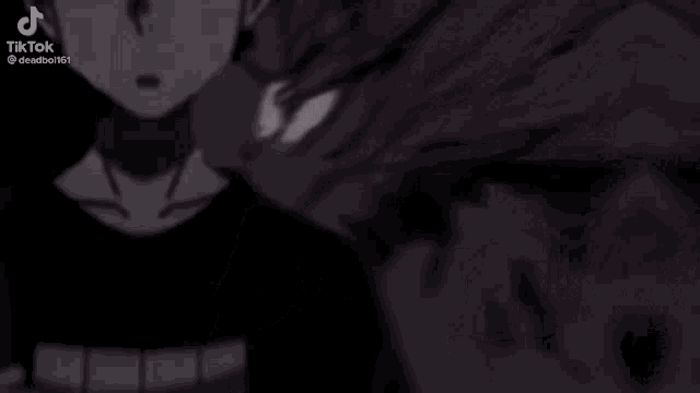 a young man in a black shirt is standing in the dark .