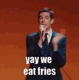 a man singing into a microphone with the words yay we eat fries